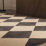 Close up of the Aradia Charcoal Area Rug, a hand-tufted wool rug with a bold charcoal and cream diamond pattern. Styleshot