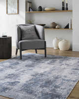 Living room scene with a gray chair on the Anitra Off White Washable Area Rug, creating a contemporary, neutral space. Roomscene-Rectangle