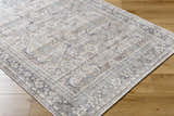 Close-up of the Zahar Washable Area Rug. Light silver, silver gray, and warm gray traditional pattern. Corner