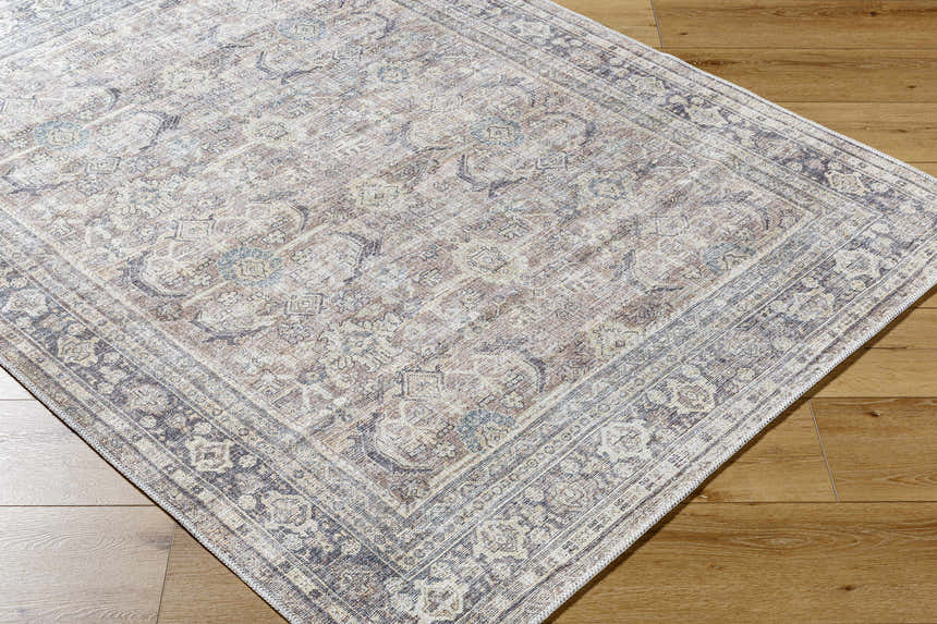 Close-up of the Zahar Washable Area Rug. Light silver, silver gray, and warm gray traditional pattern. Corner