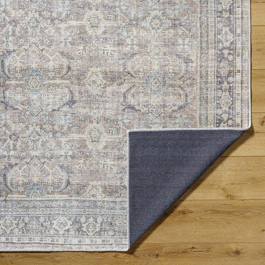 Close-up of Zahar Washable Area Rug showing traditional light silver, gray, and warm gray pattern and texture on wood floor. Fold