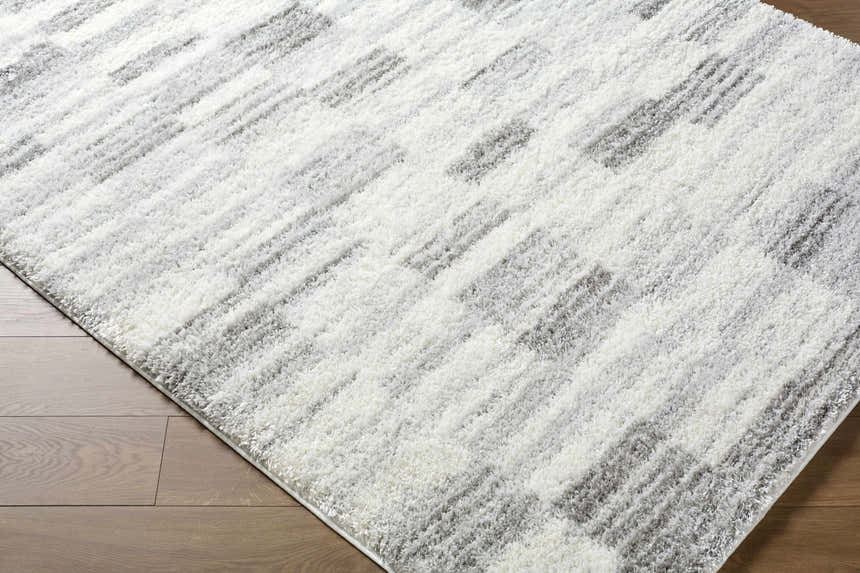 Close up of the ivory and peach Alaura Area Rug with a contemporary shag design. Corner