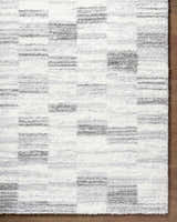 Close-up of the ivory and peach Alaura Area Rug with a contemporary shag design and geometric pattern. Corner