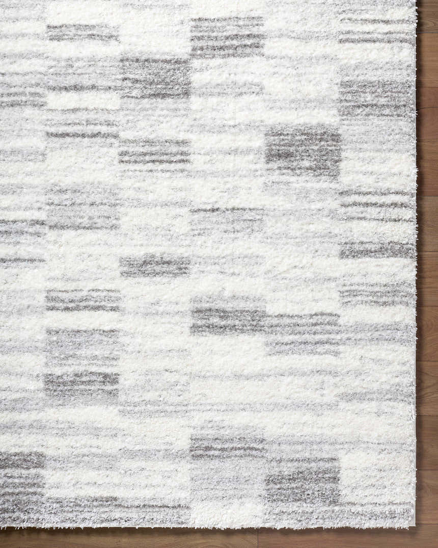 Close-up of the ivory and peach Alaura Area Rug with a contemporary shag design and geometric pattern. Corner