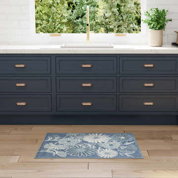 Kitchen scene with blue cabinets and Nourison Aloha Blue Outdoor Area Rug on wood floor.