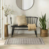 Entryway scene with a Nourison Nordic Ivory Grey rug, black bench, round mirror, and wood accents.