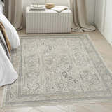Bedroom scene with a Nourison Lynx Ivory Grey Blue Vintage rug, striped ottoman, and neutral decor.