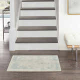 Entryway with Nourison Harmony Ivory Aqua Rug, dark wood floors, white stairs, and modern bench.