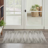 Entryway scene with a Nourison Key Largo Light Grey rug, wood floors, white doors, and a view to a garden.