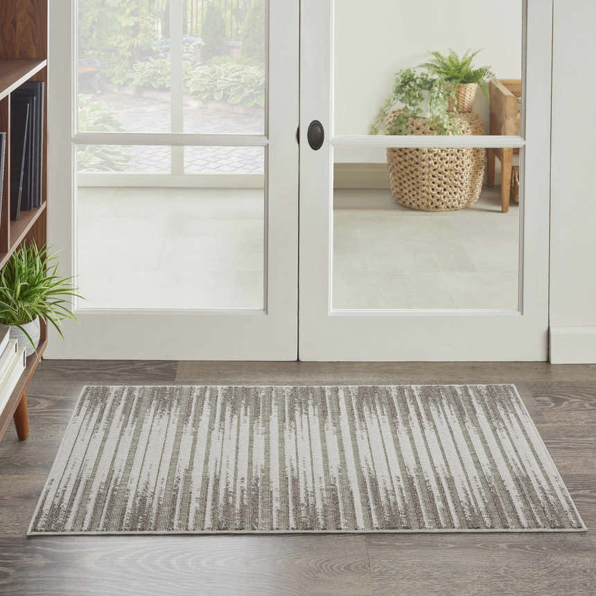 Entryway scene with a Nourison Key Largo Light Grey rug, wood floors, white doors, and a view to a garden.