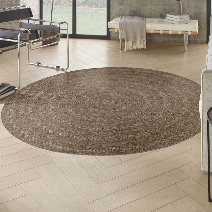Living room scene with a round Nourison Tulum Brown Outdoor Area Rug on light wood floors.