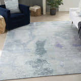 Modern living room with a blue armchair and Nourison Silk Shadows Blue Green area rug.