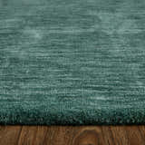 Close-up of the textured Feizy Luna Modern Solid green and white wool area rug on a wood floor. Pile
