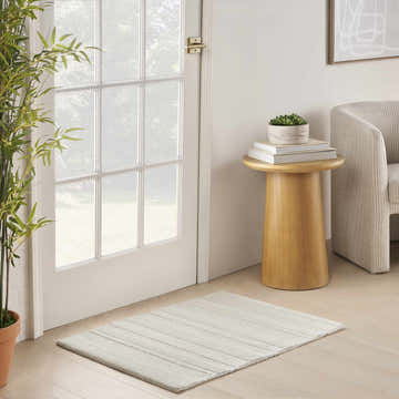 Entryway with DKNY Pure Multi Weave Ivory rug, wood floors, white door, side table, and neutral chair.