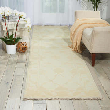 Living room scene with a Nourison Silk Pointe Ivory Vintage runner rug, chaise lounge, and white orchids.