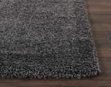 Close-up of the plush texture of the Nourison Malibu Dark Grey Shag Rug on dark wood flooring.