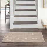 Entryway with stairs and a beige Nourison Grafix area rug with a subtle floral pattern on dark wood floors.