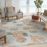 Coastal living room with Waverly Sun N' Shade Light Blue rug, seashell and coral pattern, beach view.