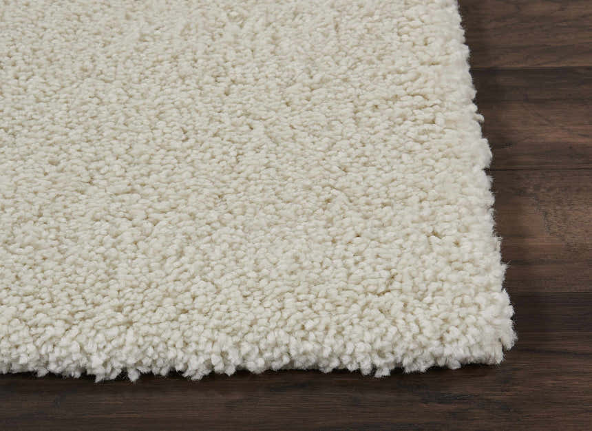 Close-up of the ivory Nourison Malibu Shag rug showing its plush texture and color on a dark wood floor.