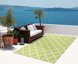 Outdoor patio scene with Nourison Home & Garden Light Green Contemporary Area Rug, wicker sofa, and ocean view.