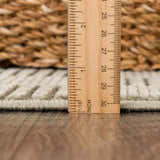 Close-up of the Kazuma Green Washable Area Rug showing the pile height with a ruler. Woven texture in gray green. Pile