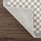 Close-up of the Gaiwan Cream Gray Washable Area Rug showing its checkerboard pattern and non-slip backing. Fold