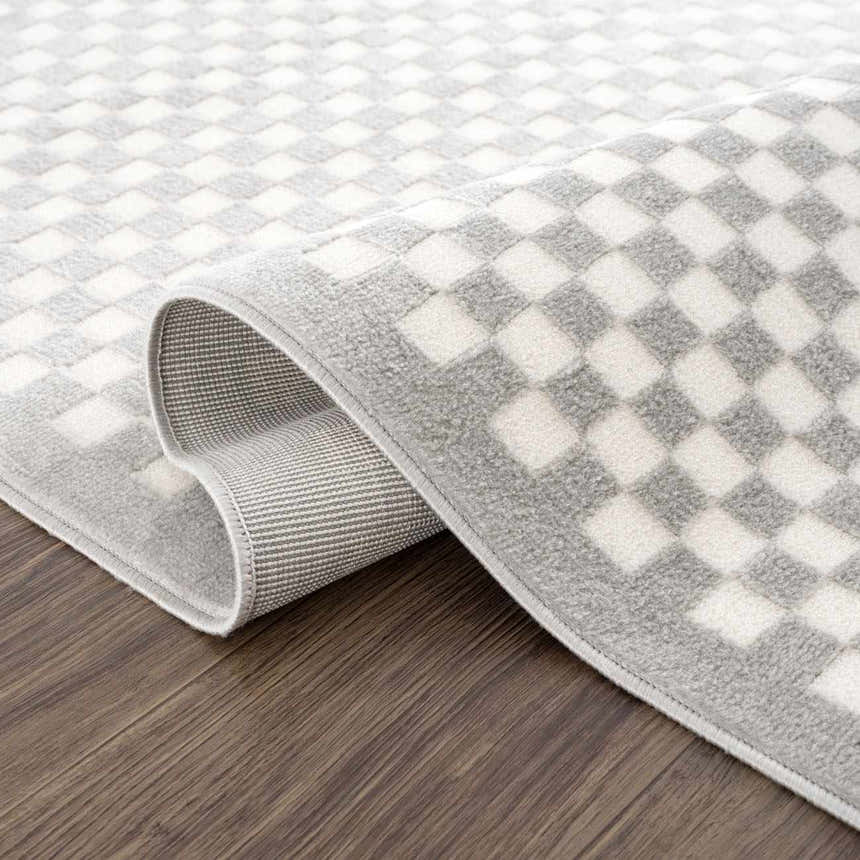 Close-up of the Gaiwan Cream Gray Washable Area Rug, featuring a light gray and off-white checkered pattern. Fold