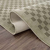 Close-up of Gaiwan Olive Green Washable Area Rug showing its gray green checkered design and durable, machine-woven construction. Fold