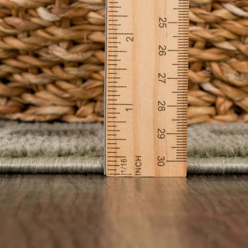 Close-up of Gaiwan Olive Green Washable Area Rug showing pile height with a ruler and basket weave texture in the background. Pile