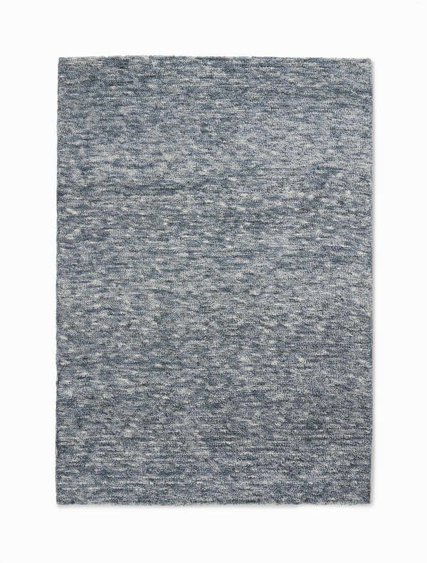 Close-up of the Calvin Klein Tulsa Denim Plush Rug. Features a textured, heathered denim blue and white design.