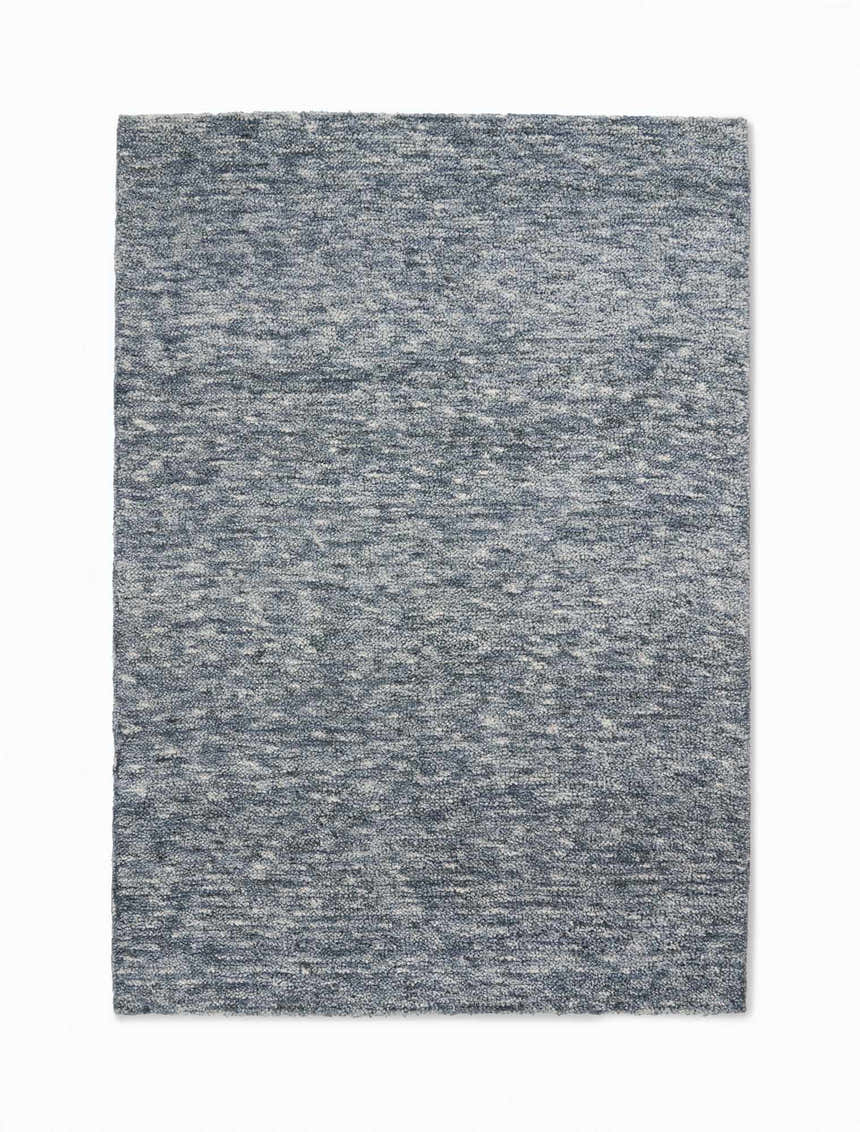 Close-up of the Calvin Klein Tulsa Denim Plush Rug. Features a textured, heathered denim blue and white design.