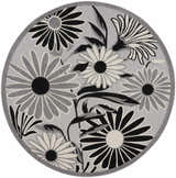 Close-up of a round Nourison Aloha Black White Outdoor Area Rug with a black and white floral pattern on a gray background.