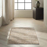 Minimalist room scene with a Calvin Klein Mesa Amber rug, light wood floors, linen curtains, and a black accent table.