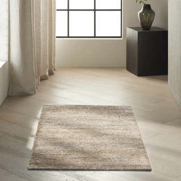 Minimalist room scene with a Calvin Klein Mesa Amber rug, light wood floors, linen curtains, and a black accent table.
