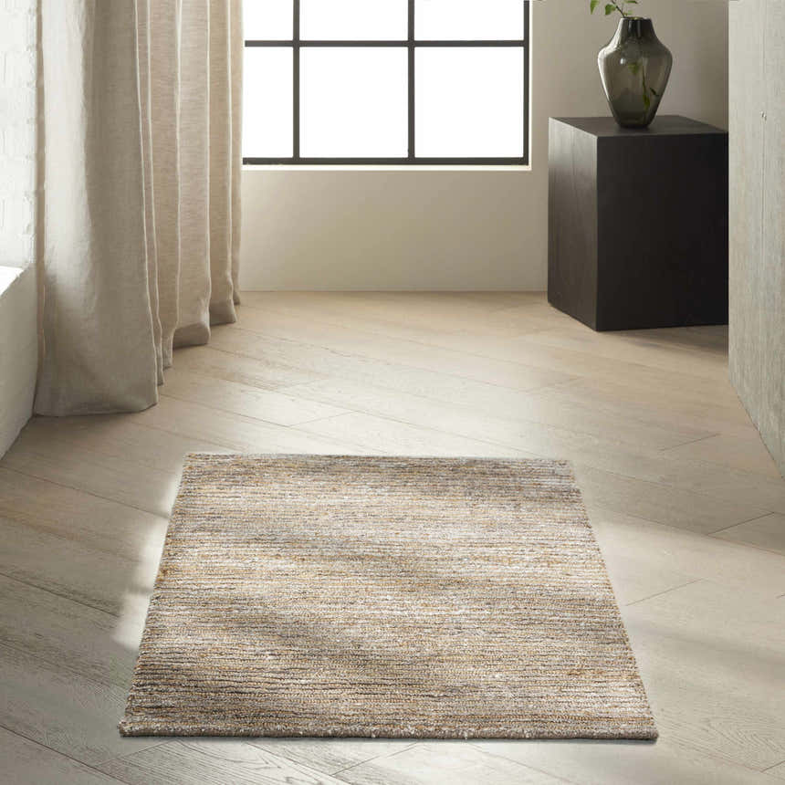 Minimalist room scene with a Calvin Klein Mesa Amber rug, light wood floors, linen curtains, and a black accent table.