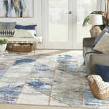 Living room scene with a Nourison Elation Grey Multicolor rug, gray sofa, white bench, and blue and white pillows.
