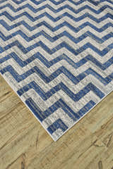 Close-up of Feizy Brixton rug featuring a modern blue, ivory, and gray chevron pattern on a wood floor. Corner
