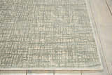 Close up of Nourison Starlight Sea Mist rug showing its subtle geometric pattern and soft texture on a wood floor.