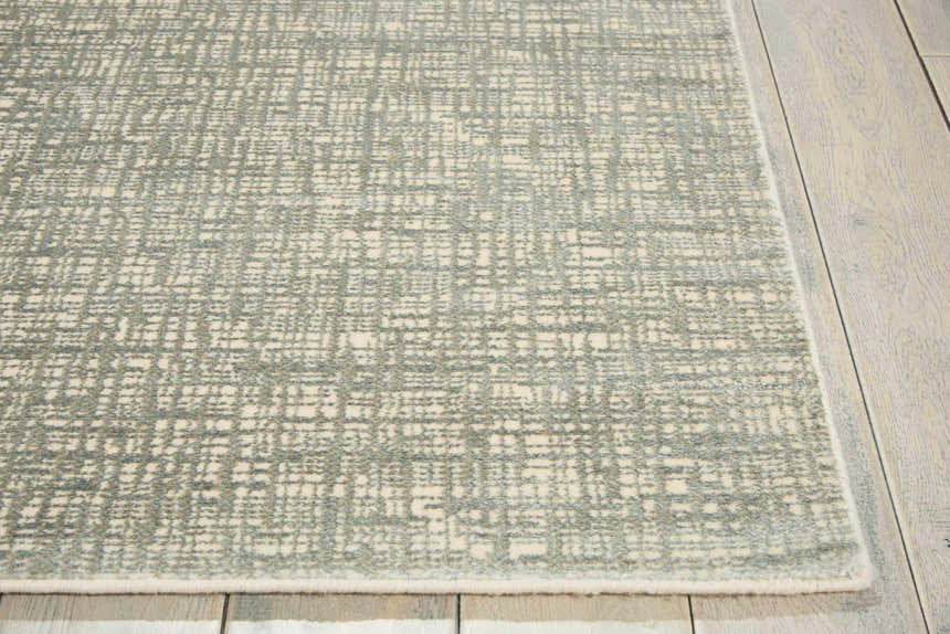 Close up of Nourison Starlight Sea Mist rug showing its subtle geometric pattern and soft texture on a wood floor.