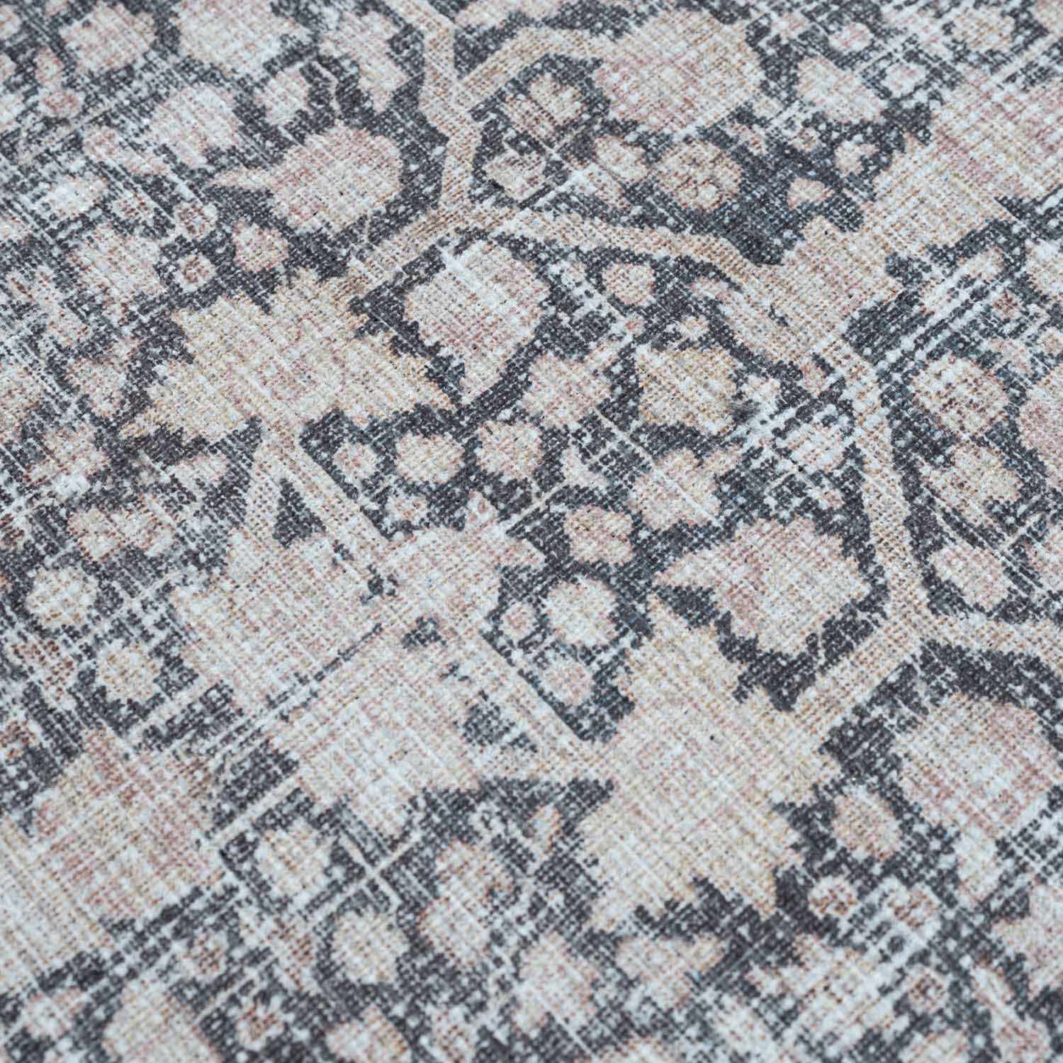 Close-up of the Hedda Boutique Washable Rug. Features a traditional, vintage pattern in dark gray, nutmeg, and light gray hues. Texture