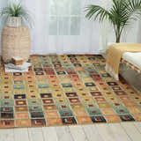 Bright room scene with multicolor Nourison Aristo rug. Geometric pattern in shades of gold, orange, blue, and brown.