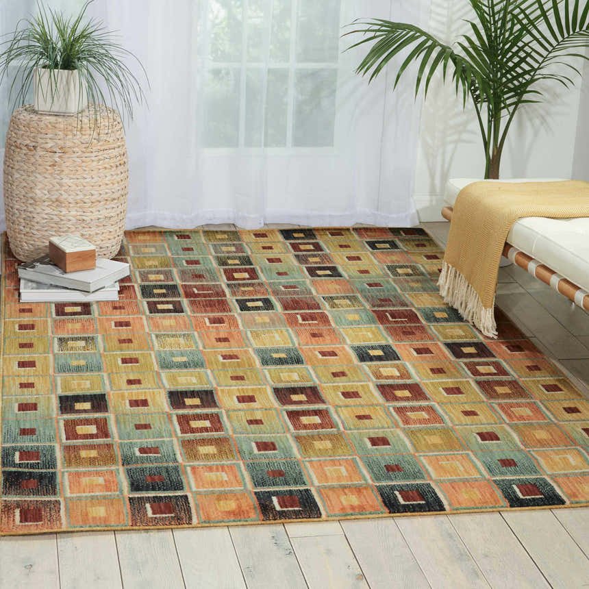 Bright room scene with multicolor Nourison Aristo rug. Geometric pattern in shades of gold, orange, blue, and brown.