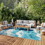 Coastal patio with gray furniture and Nourison Color Splash Ivory Blue rug with wave design on wood deck.