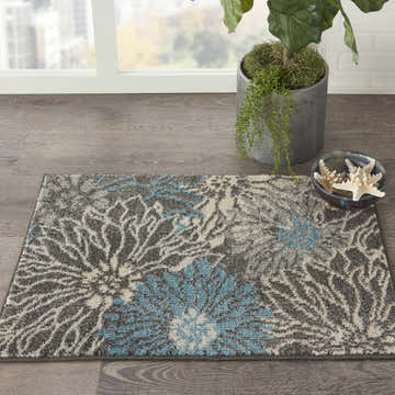 Close-up of Nourison Passion Charcoal Blue rug with floral design, taupe and blue accents on wood floor.