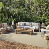 Outdoor patio with gray furniture on a Nourison Courtyard Jute Ivory Modern Area Rug. Lush green plants in the background.