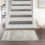 Entryway with Nourison Quarry Ivory Grey rug, dark wood floors, white stairs, and modern white bench.