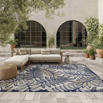 Outdoor patio scene with a beige sectional sofa on a Nourison Aloha Ivory Navy Tropical Area Rug.