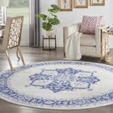 Living room scene with round Nourison Whimsicle Ivory Blue rug, chair, desk, and plant. Farmhouse style.