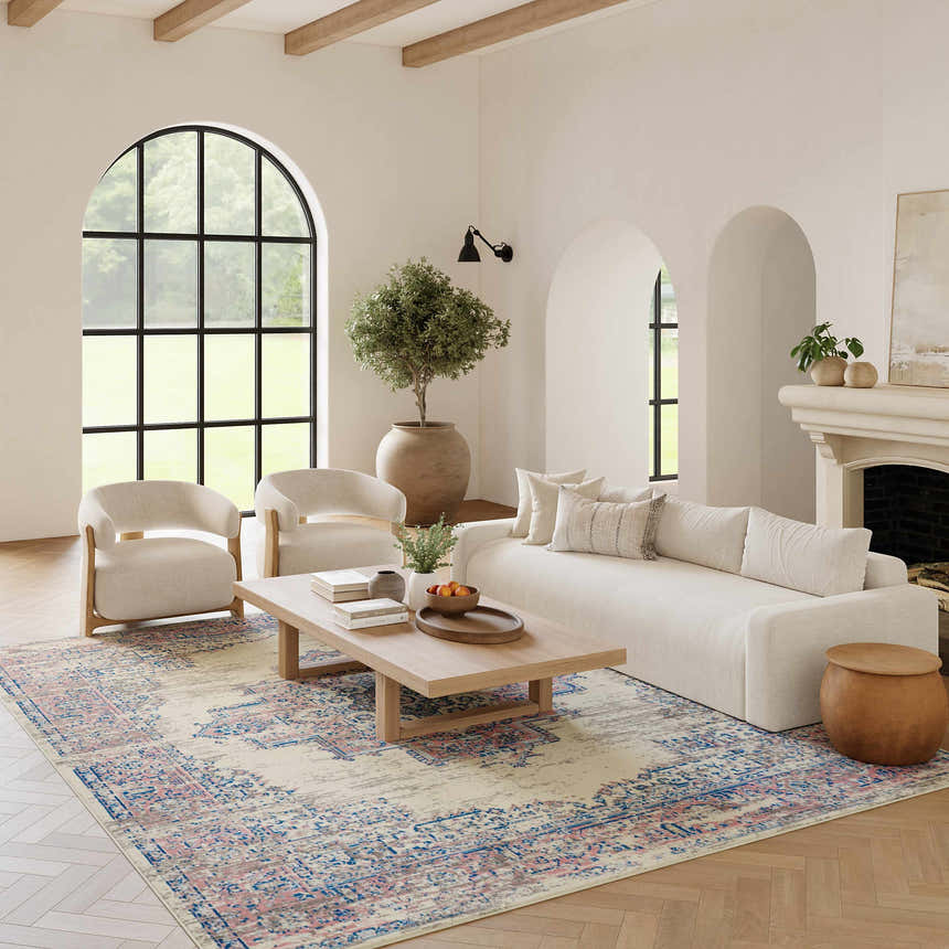 Living room scene with a Nourison Grafix Ivory Pink Vintage rug, cream sofa and chairs, and light wood accents.