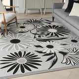 Living room scene with a Nourison Aloha Black White Outdoor Area Rug featuring a floral pattern.